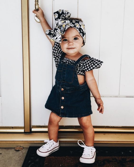 Little girl wearing a fabric headband and a denim dress