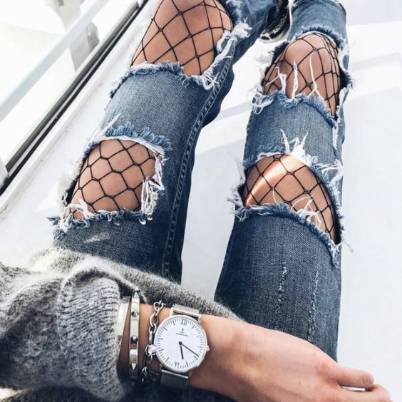Jeans with holes revealing fishnet tights